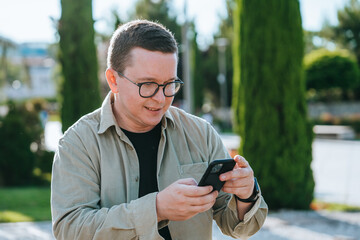 Satisfied caucasian guy in casual holds phone reading message sitting at park, traveling on vacation holidays. Smart male freelancer enjoying weekend on trip, reboot, new impressions.