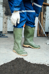 Construction worker wear blue uniform and safety rubber boots at the construction site 