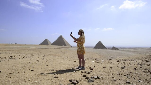 Travel influencer girl records with her mobile and talks to camera in egyptian pyramids, Gyza, Egypt
