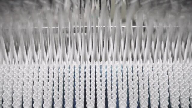 Automated machinery in Modern textile Factory. Industrial Loom producing woven fabrics for clothes in high speed - Close up.