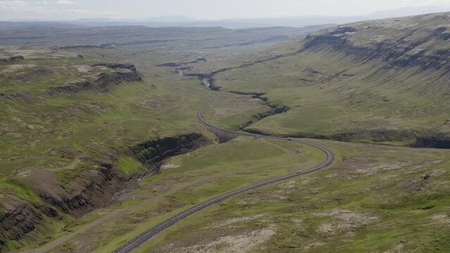 Tilting drone video in Iceland overlooking a beautiful green road winding through the lush valley near Bifrost in Northern Iceland