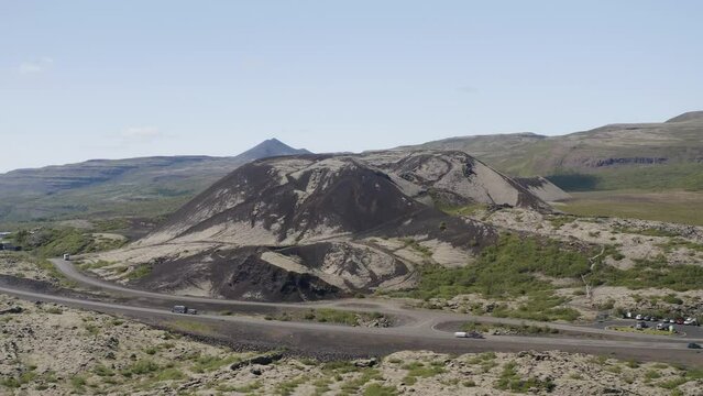 Looking across a road in Iceland at the large Gradbrok crater as it sits dormant near Bifrost in the Nordurardalur Valley