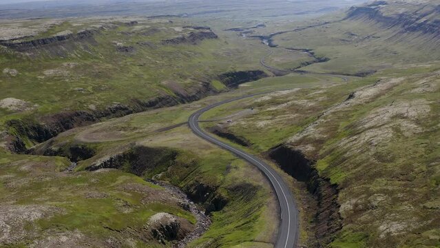 Looking over a curvey twisting road cutting through an empty valley in Iceland on a cloudy summer evening