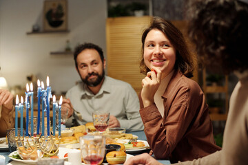 Young smiling woman looking at her husband by served festive table with homemade food and drinks...