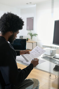 Worker sitting at his workplace reviewing a resume of a job candidate