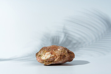 Piece of granite stone on white background with shadows