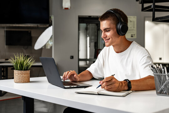 Young man wearing headphones while studying with laptop