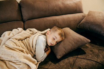 A little boy is sleeping at home on sofa.