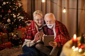 A senior couple is having video call on tablet on christmas and new year's eve.