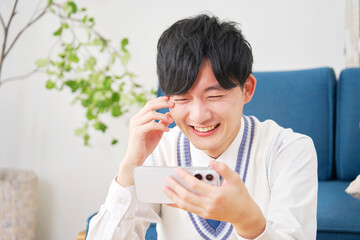 リビングでスマートフォンを見る男子高校生