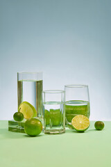 Transparent glasses of water and fresh lemons are placed on the table with a light blue background. Fresh space with fresh lemon rich in vitamin C. Copy space for ads.