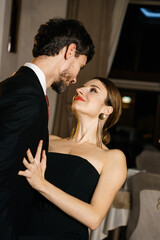 A stylish man and woman in evening wear, a suit and a dress, posing against the backdrop of a luxurious hotel. Casino concept