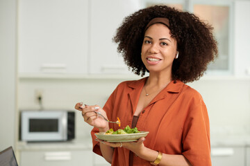 Portrait of smiling woman with curly fluffy hair eating tuna salad for lunch