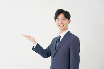 手のひらで左側を指すビジネスマン　白背景