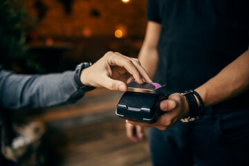 Close up of a hand paying with credit card on POS machine.