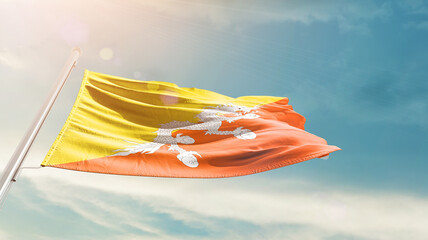 Bhutan national flag waving in beautiful sky. The symbol of the state on wavy silk fabric.