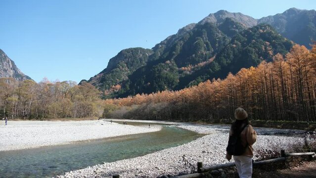A female tourist walking and looking at a beautiful autumn view in Kamikochi, Japan