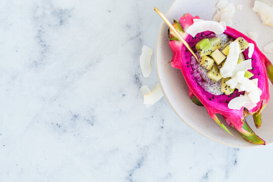 Half of pink pittaya stuffed with chia pudding, kiwi and coconut. Healthy vegan food.