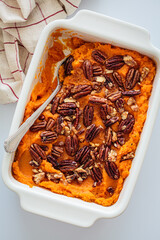 Traditional sweet potato casserole with pecan, white background.