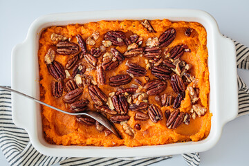 Traditional sweet potato casserole with pecan, white background.