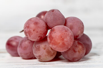 Fresh purple grapes on a white wooden background. Organic agricultural products. Delicious bunch of grapes