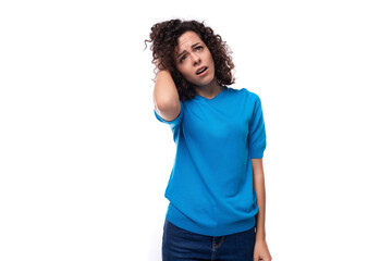 a slender young curly woman dressed in a blue summer jacket touches her hair