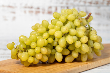 Fresh green grapes on a white wooden background. Organic agricultural products. Delicious bunch of grapes
