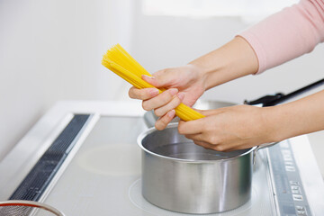 キッチンでスパゲッティを調理する女性