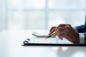 Businessman uses pen to point at chart Graph and use ideas to analyze financial reporting...