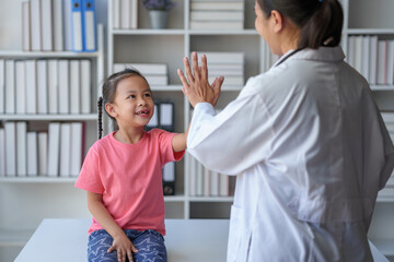 A female doctor stands and holds a file of a young patient's medical history. She uses her hand to...