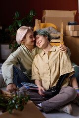 Vertical image of lovely lesbian girls enjoying the time together while unpacking things in the room