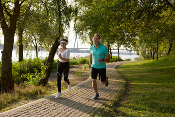 Older married couple enjoying jogging exercise during beautiful sunny summer day