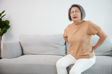 senior woman suffering from back pain on sofa