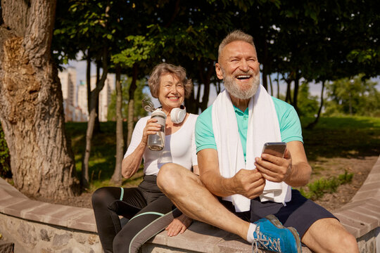 Happy overjoyed elderly man and woman couple enjoying sunny day after jogging