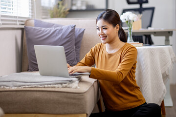 Happy casual beautiful asian woman using laptop at home.