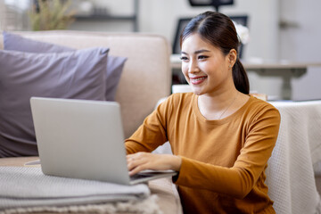 Happy casual beautiful asian woman using laptop at home.