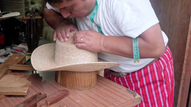 An adult Hispanic man is shaping a natural fiber hat in a workshop. Concept of handmade traditional clothing