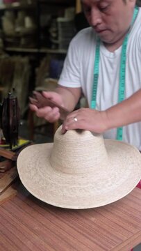 An adult Hispanic man is shaping a natural fiber hat in a workshop. Concept of handmade traditional clothing