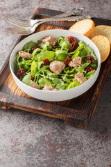 Healthy food cod liver salad with mixed leafy greens and sun-dried tomatoes close-up in a bowl on the table. Vertical