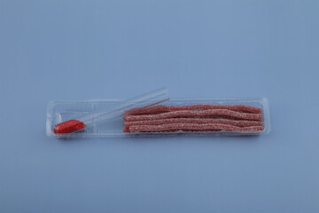 Food coloring Tartrazine in glass test tube and chewing sweets.