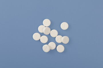 White pills or tablets on blue background. Concept Placebo effect in medicine. Tendency increased consumption of medications, antidepressants and sedative pills