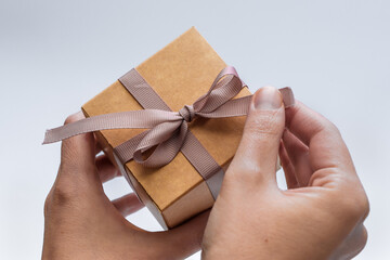 Rozpakowywać prezent, pudełeczko ozdobione kokardką trzymane w dłoniach z bliska