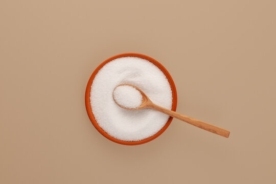 Xylit powder or birch sugar in plate with spoon, top view. Food additive E967, sweetener. Xylitol is used as sugar substitute in drugs, dietary supplements, confections, toothpaste, and chewing gum
