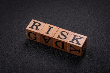 The inscription risk with wooden cubes on a dark concrete background