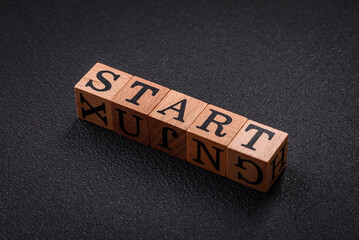 The inscription start on wooden cubes on a dark concrete background
