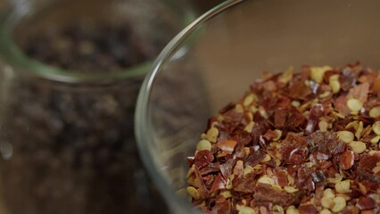 Closeup view of jars containing spices for chimichurri sauce, black pepper and dried red chili