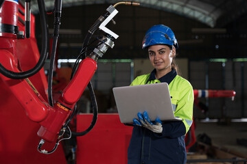 Female engineer inspecting quality and maintenance autonomous robotics arm system welding in factory