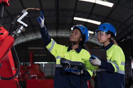 Team of female engineer inspecting quality of autonomous robotics arm. Group of technician maintenance and control robotics arm in factory