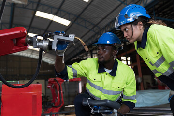 Fototapeta premium Male and female engineer repair autonomous robotics arm. Group of technician maintenance and control robotics arm in factory