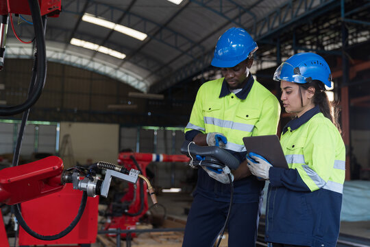Male and female engineer repair autonomous robotics arm. Group of technician maintenance and control robotics arm in factory